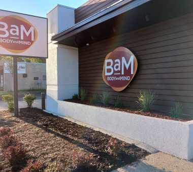 Exterior view of a building with signage for 'BaM BODY and MIND' in the sunlight