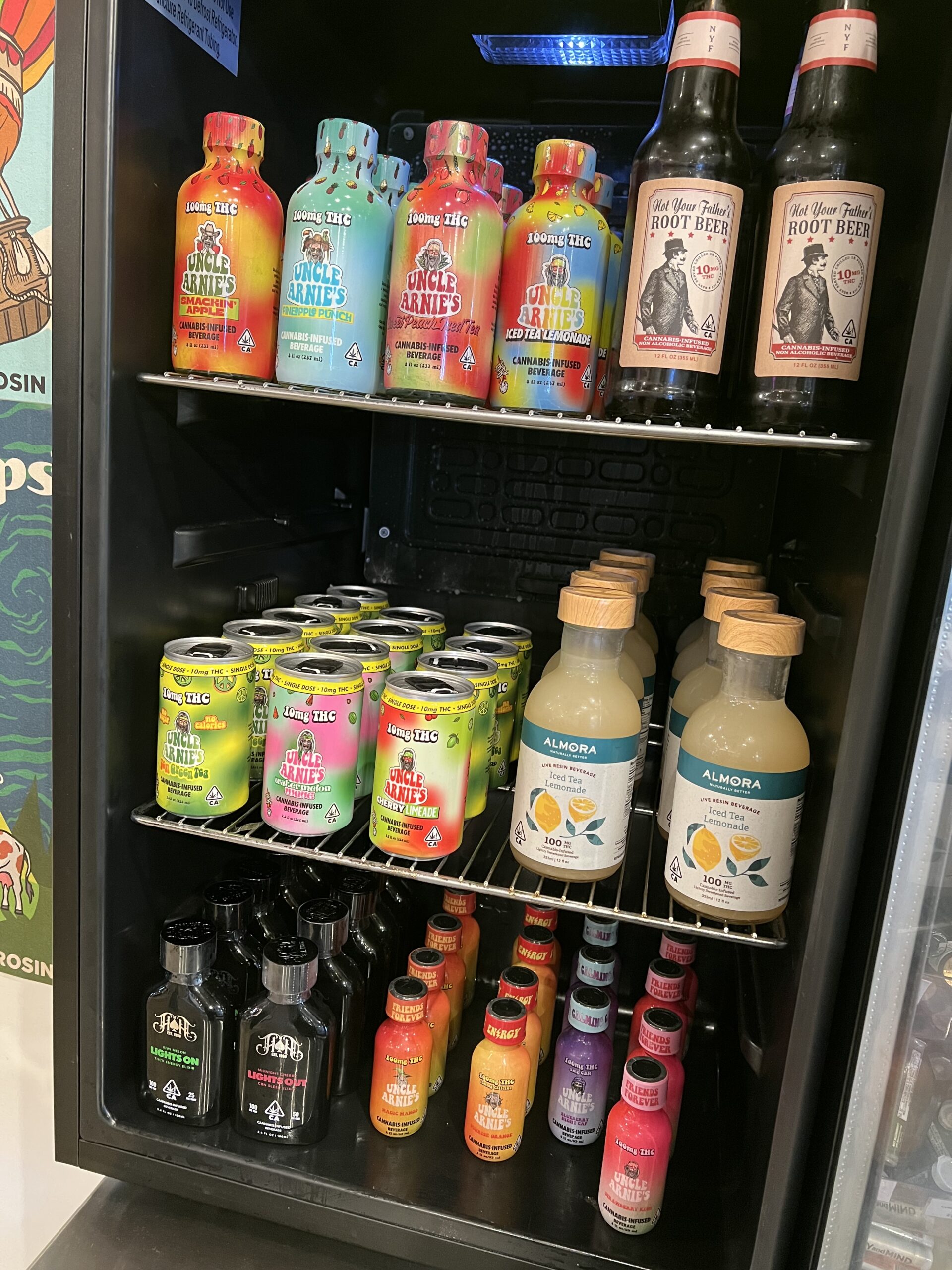 Assorted colorful beverage bottles and cans neatly arranged on refrigerator shelves